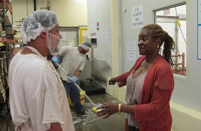 Daphne Jones, owner of Glorious Malone’s Fine Sausage, Inc., talks with employee Nick Reynosa at her plant at Martin Luther King Drive and Walnut Street. (Photo by Andrea Waxman)