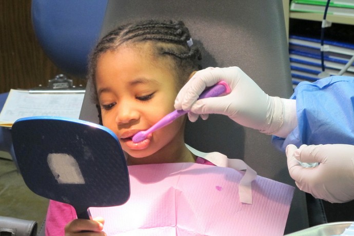Arielle Williams observes the proper brushing technique demonstrated by Smart Smiles dental assistant Calandria Duncan. (Photo by Andrea Waxman)