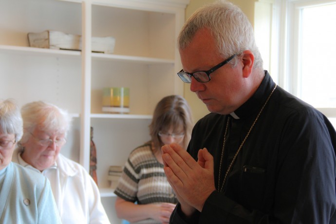 Auxiliary Bishop for the Archdiocese of Milwaukee Donald J. Hying leads friends and supporters of the Clare Community project in prayer at a celebration of the new women’s shelter.  (Photo by Karen Slattery) 