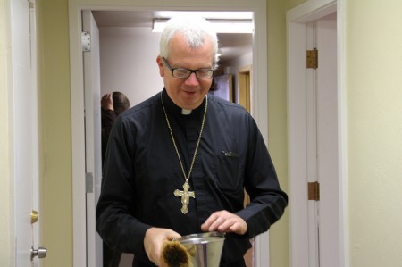Bishop Donald J. Hyling walks through the new Clare Community apartment sprinkling holy water to bless the new facility.  (Photo by Karen Slattery)