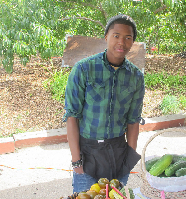 Cameron Nash, an intern for the Garden 2 Market program, sells fresh produce grown in Walnut Way gardens at Harvest Day. (Photo by Molly Rippinger).