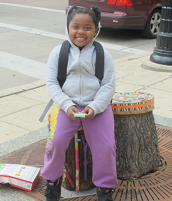 Jasmine Johnson made use of a colorful “LUV” seat while waiting for the bus with her mother, Deborah.
