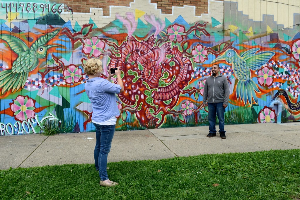 Caitlin Sprague, creator of the Milwaukee Mural Map, photographs muralist Ramiro Sandoval Arguta in front of "The Hummingbirds," at 22nd Street and National Avenue. (Photo by Sue Vliet)