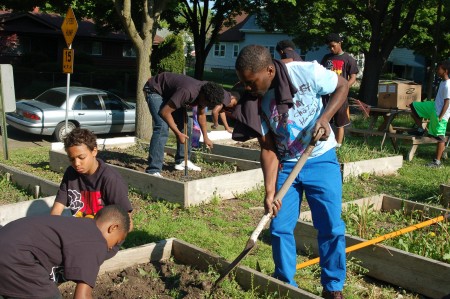 Trevis Hardman (in white T-shirt), 22, who grew up across the street from the garden at 9th and Ring streets, works with the boys. (Photo by Andrea Waxman) 