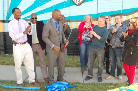 Alderman Russell W. Stamper II cuts a ribbon as community leaders and Washington Park residents celebrate a new mural marking the neighborhood's entrance. (Photo by Andrea Waxman)