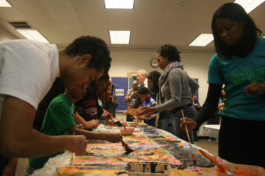 Milagro Jones (front left), Mayor Barrett (back) and others paint one of two canvases for the King Library's community mural on MLK Day. (Photo by Jabril Faraj)