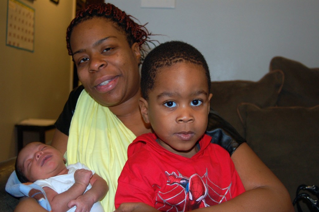 Nicole Roundtree holds her week-old son Joel and her 3-year-old son Elijah in her apartment at Nia Imani. (Photo by Andrea Waxman)