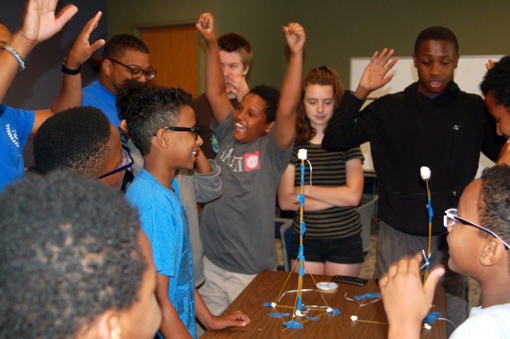 Winners of the “marshmallow challenge” celebrate their victory. (Photo by Andrea Waxman)