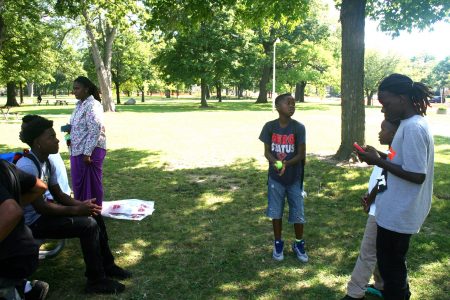 Young people, including Niekale Steward (seated), hang out at Sherman Park. (Photo by Jabril Faraj)