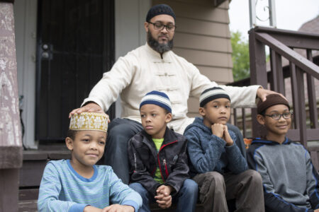 Nazir Al-Mujaahid, and his sons, sitting on the steps in front of their home.
