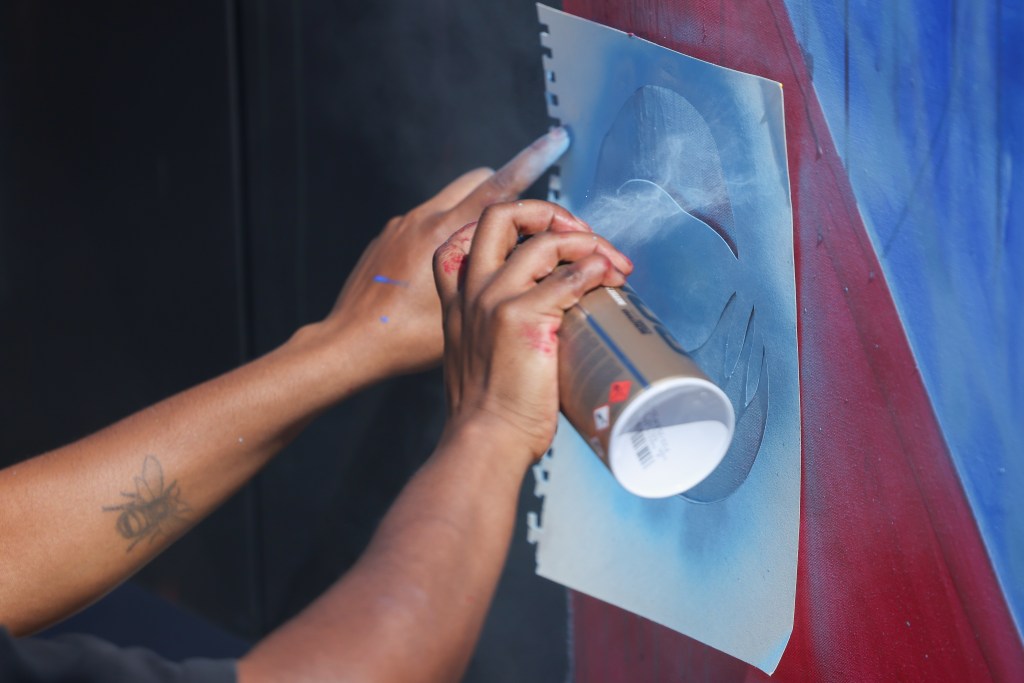 A person works on a mural during the TRUE Skool Juneteenth mural contest during the 55th Juneteenth Jubilee Parade on Friday, June 19, 2026 in Milwaukee. (Photo by Jonathan Aguilar / Milwaukee Neighborhood News Service / CatchLight Local)