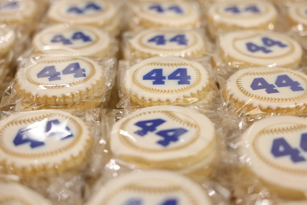 Wrapped cookies decorated with white icing and the number "44" in blue are arranged in rows.
